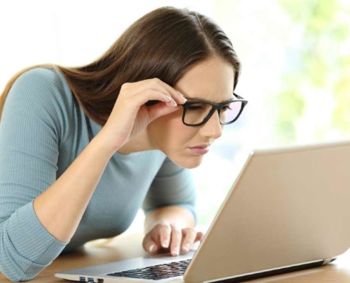 woman squinting to see computer screen