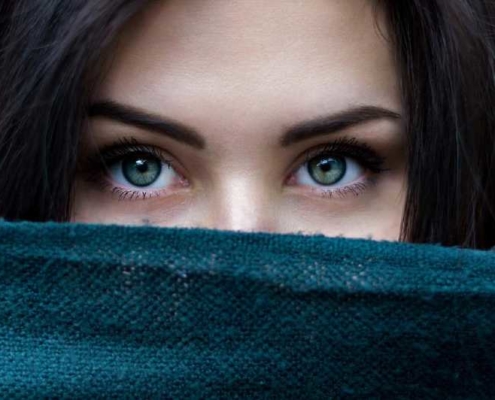 dark haired green eyed woman peeking over cloth