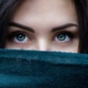 dark haired green eyed woman peeking over cloth